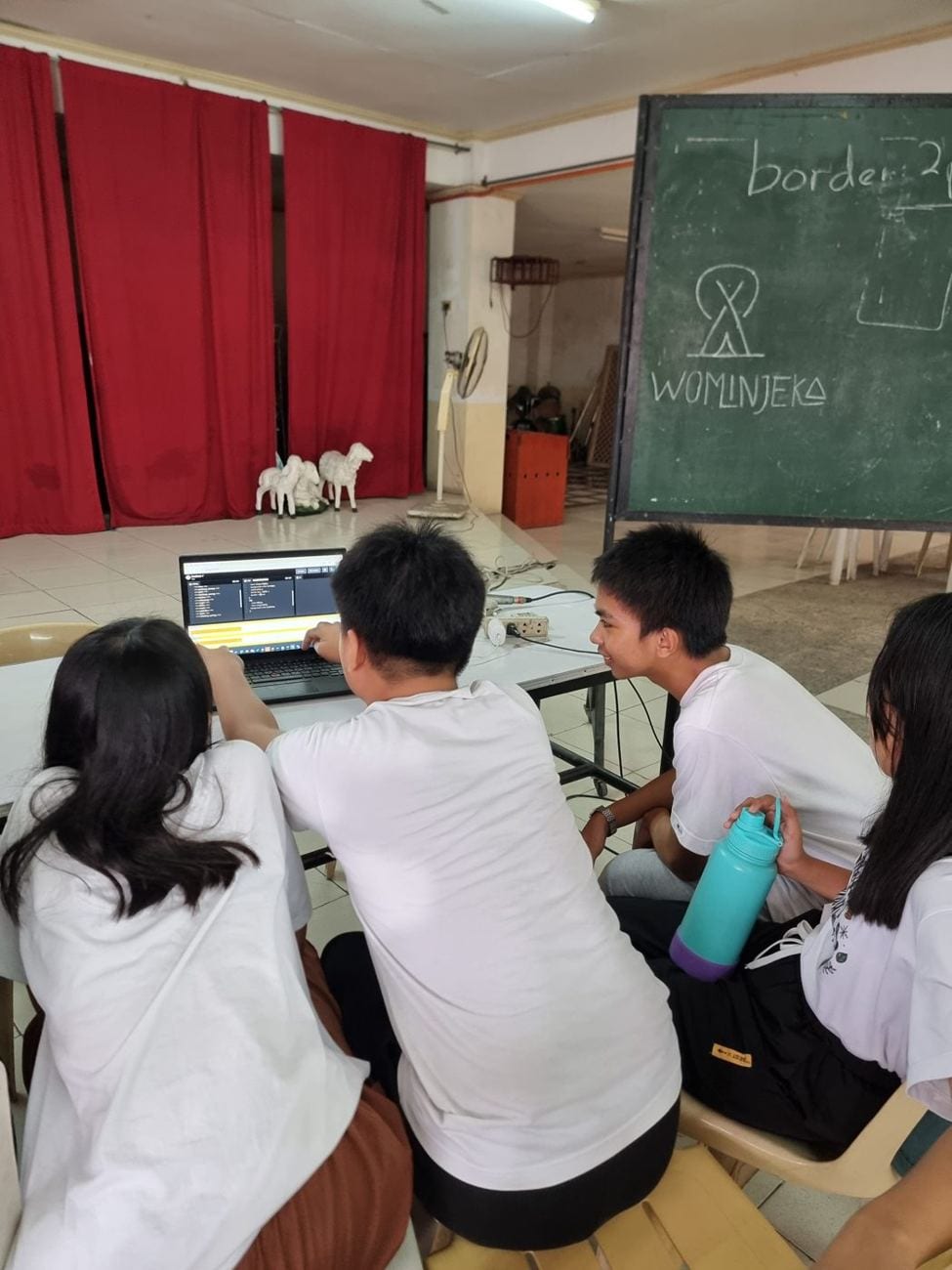 Students working together at a laptop during a session
